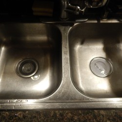 A sink with plugs in the drain and a small amount of standing water.