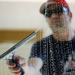 Picture of a man outside washing a window.
