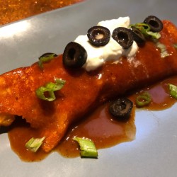 Cheese-Wrapped Chicken Enchilada on plate with sour cream & olives