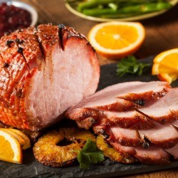 Honey baked ham with cloves, partially sliced.