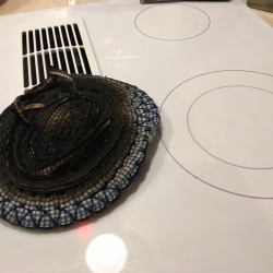 A burned hot pad next to a clean smooth top stove burner.