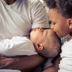 Young child kissing a newborn.