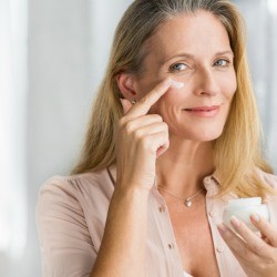 Woman applying moisturizer.