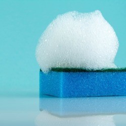 Blue sponge with soap foam on top.