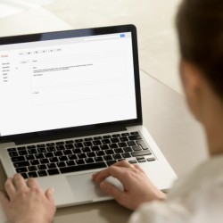 A woman writing an email on a laptop computer.