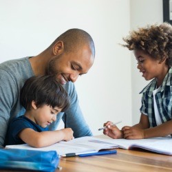 Father helping his sons with worksheets.