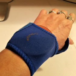 A wrist brace and a metal canning jar insert on a woman's wrist.