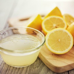 Bowl of lemon juice next to cut lemons.