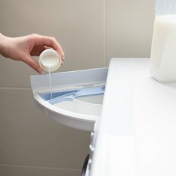 Hand pouring liquid fabric softener into washing machined soap dispenser.