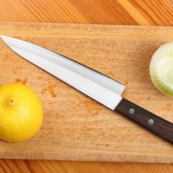 Lemon, onion and kitchen knife on a wooden board