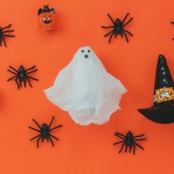 Gauze ghost on orange surrounded by spiders.