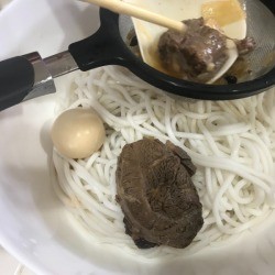 Leftover broth being strained before being added to a bowl.