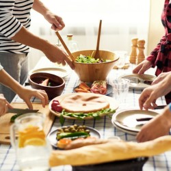 A dinner party with many young adults serving from a counter.