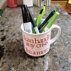A mug holding pens on a countertop.