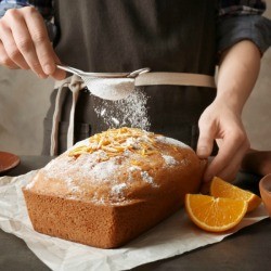 sprinkling powdered sugar on a loaf cake
