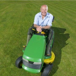 man sitting on a green and yellow riding mower