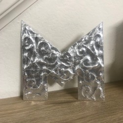 Foil Wrapped Cardboard Letter - letter standing on the floor next to the stairs