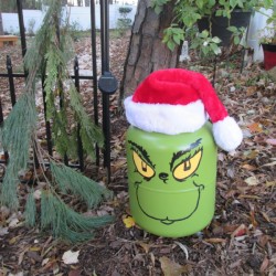 Helium Tank Upcycled as The Grinch - Grinch sitting on the ground outside 
