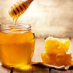 Jar of honey next to pieces of honeycomb