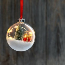 Clear Christmas ornament filled with tree, snow and a present.