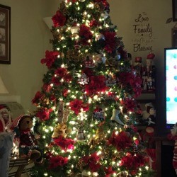 An artificial Christmas tree decorated with poinsettias and white lights.