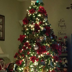 An artificial Christmas tree decorated with poinsettias and white lights.