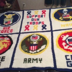A large crocheted wall hanging with a military theme.