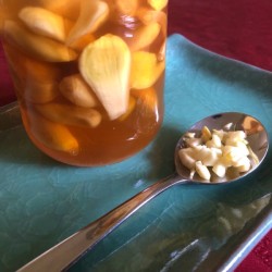 A spoonful of minced garlic next to a mixture of garlic and honey.