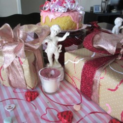 Recycled Paper Rolls as Heart Stamps - packages wrapped in the stamped paper sitting on a table covered with pink and white striped fabric stamped with red hearts 