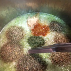 The different spices and seasonings for a recipes spread out on the top of the soup.