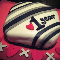 A decorated cake celebrating a 1 year anniversary.