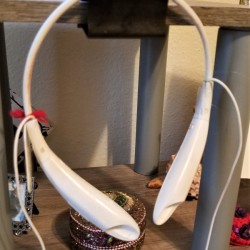 A binder clip holding a pair of bluetooth headphones.