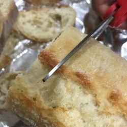 A loaf of bread being cut with a pair of scissors.