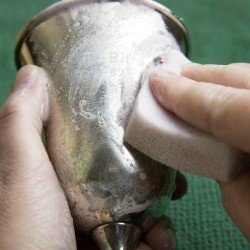 A silver goblet being polished.