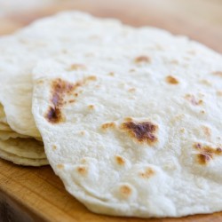 Homemade Tortillas piled on a cuttingboard