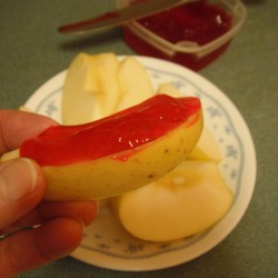 An apple slice with strawberry glaze topping it.
