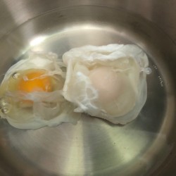 Two eggs poaching in water.