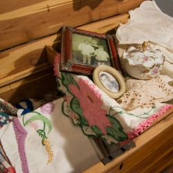 A hope chest with old fashioned linens and photos.