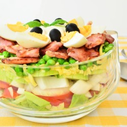 A green layered salad in a clear bowl.