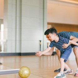 Dad helping son bowl.