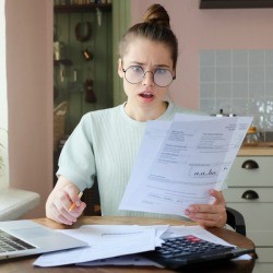A shocked woman reviewing a utility bill.
