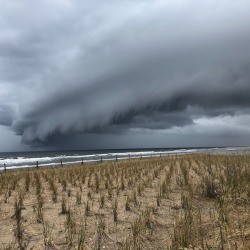 Dark stormclouds over the ocean and a field.