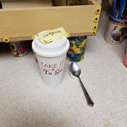 A plastic lid being used as a small spoon rest for coffee.