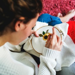 Removing Embroidery Transfers From Fabric - young woman working on sunflower embroidery pattern